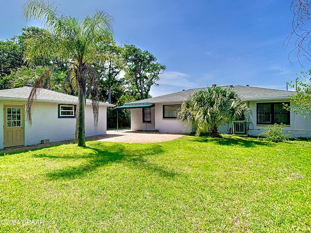 back of property featuring stucco siding, an outbuilding, a patio, and a yard