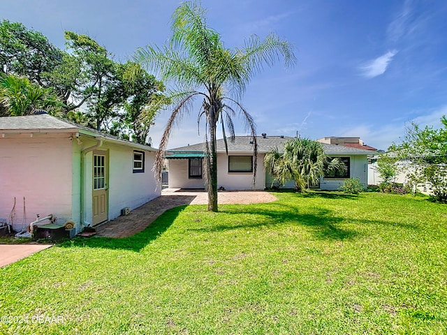 back of house with a patio, a lawn, and stucco siding