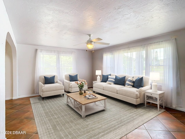 living area with arched walkways, tile patterned flooring, plenty of natural light, and a textured ceiling