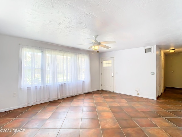 interior space with visible vents, baseboards, a ceiling fan, tile patterned flooring, and a textured ceiling