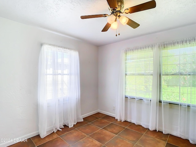 unfurnished room featuring dark tile patterned flooring and baseboards