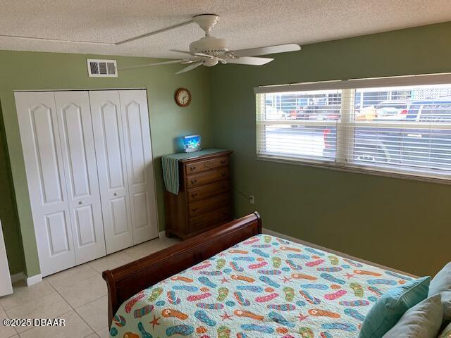 325 Causeway Cswy N Unit D104, New Smyrna Beach, FL 32169 - bedroom featuring a closet, a ceiling fan, a textured ceiling, light tile patterned floors, and visible vents