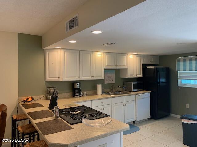 325 Causeway Cswy N Unit D104, New Smyrna Beach, FL 32169 - kitchen featuring light countertops, dishwasher, stainless steel microwave, a sink, and freestanding refrigerator