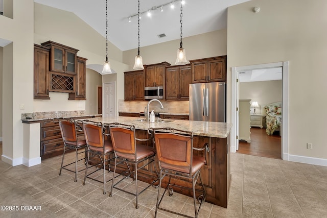 1329 Sunningdale Ln, Ormond Beach, FL 32174 - kitchen with stainless steel appliances, light tile patterned floors, decorative backsplash, a kitchen bar, and light stone counters