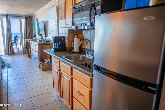 kitchen featuring light tile patterned floors, sink, ornamental molding, backsplash, and stainless steel fridge