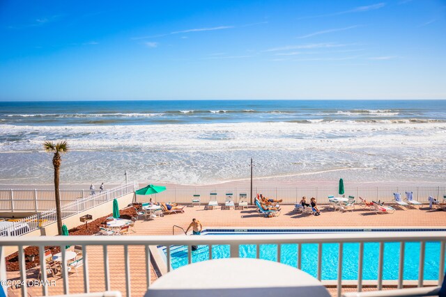 view of swimming pool featuring a view of the beach and a water view