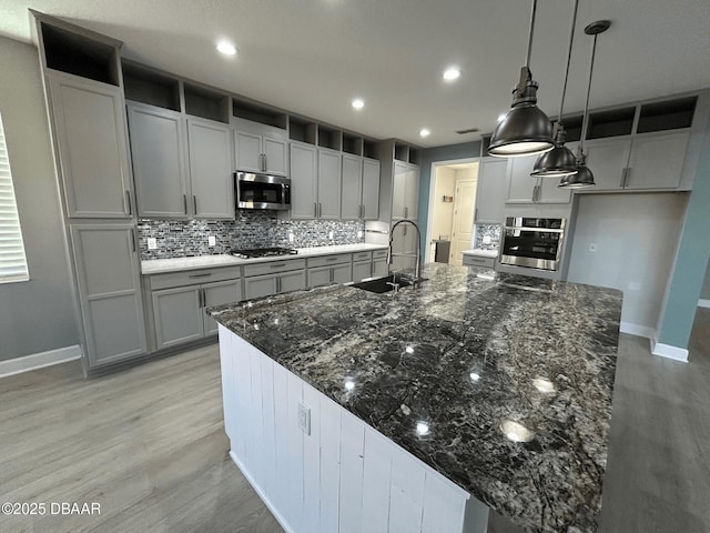 kitchen featuring sink, hanging light fixtures, dark stone countertops, appliances with stainless steel finishes, and backsplash