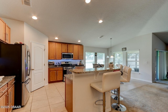 kitchen with light tile patterned floors, a kitchen breakfast bar, lofted ceiling, and appliances with stainless steel finishes