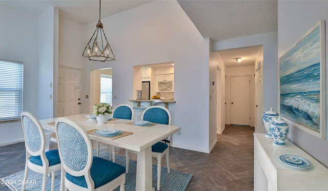 dining room with a towering ceiling, a wealth of natural light, and dark parquet flooring