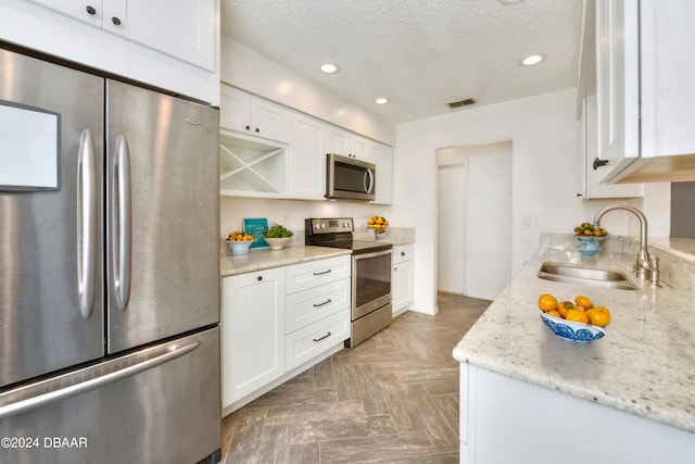 kitchen with white cabinets, sink, dark parquet flooring, and stainless steel appliances