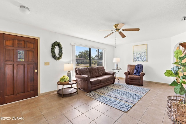 living room featuring ceiling fan, light tile patterned floors, and a textured ceiling