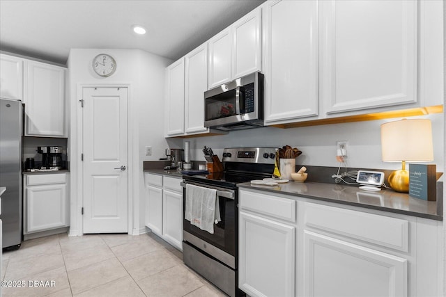 1223 Cabot Cliffs Dr, Daytona Beach, FL 32124 - kitchen with dark countertops, light tile patterned floors, recessed lighting, appliances with stainless steel finishes, and white cabinetry
