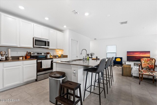 1223 Cabot Cliffs Dr, Daytona Beach, FL 32124 - kitchen featuring visible vents, a breakfast bar, appliances with stainless steel finishes, white cabinetry, and a sink
