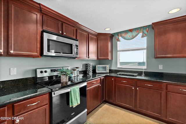 kitchen with dark stone countertops, light tile patterned floors, a textured ceiling, and appliances with stainless steel finishes