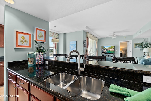 kitchen with dark stone countertops, ceiling fan, sink, and decorative light fixtures