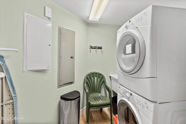 washroom with stacked washer / dryer, electric panel, wood-type flooring, and a textured ceiling