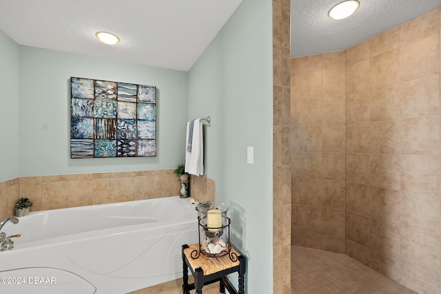 bathroom with a textured ceiling and shower with separate bathtub