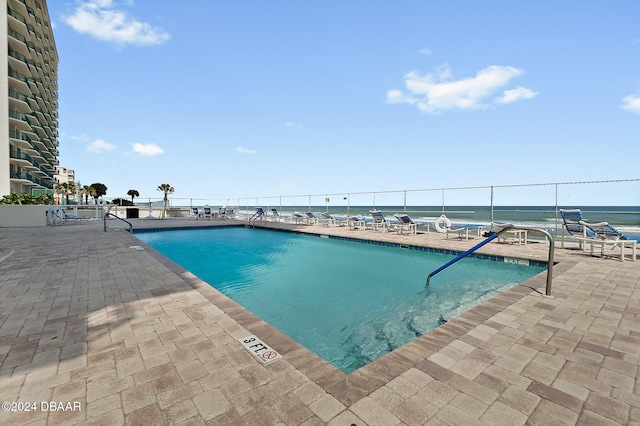 view of swimming pool featuring a water view and a patio