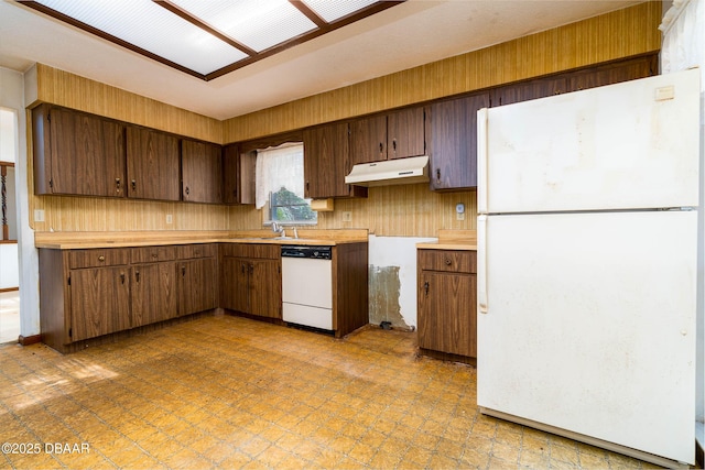 kitchen with white appliances, under cabinet range hood, a sink, and light countertops