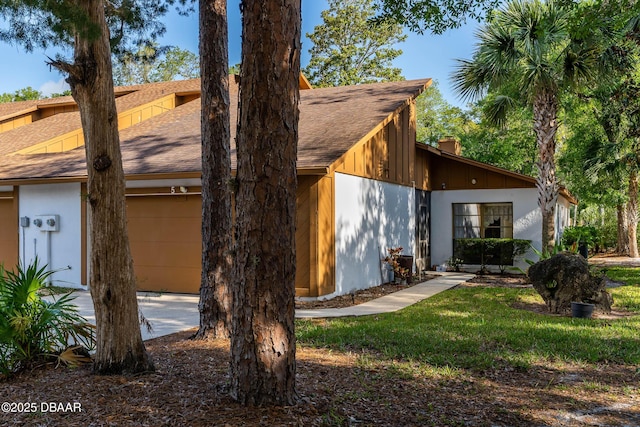 back of house with a garage, a chimney, and roof with shingles
