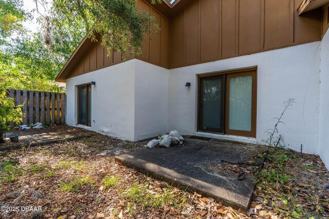 rear view of house featuring board and batten siding and fence
