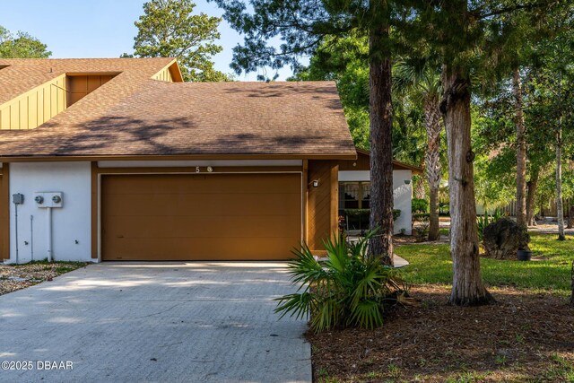 view of front facade with an attached garage, driveway, roof with shingles, and stucco siding