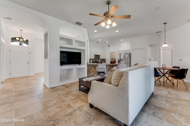 living room featuring built in shelves and ceiling fan with notable chandelier