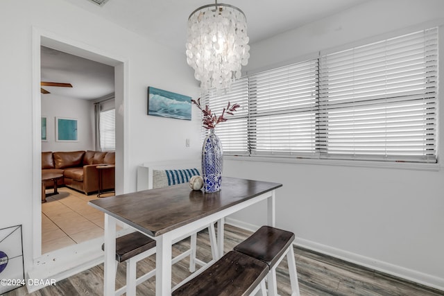 dining space with wood-type flooring and ceiling fan with notable chandelier