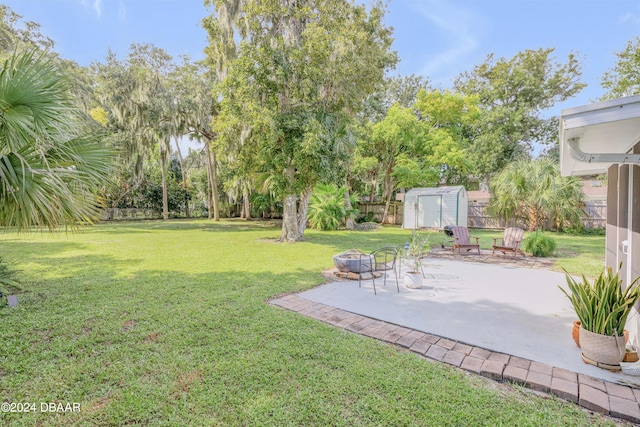 view of yard featuring an outdoor fire pit, a storage shed, and a patio area