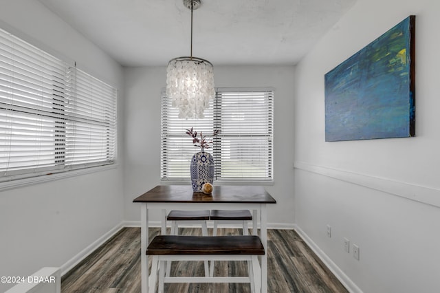 dining room with dark wood-type flooring and an inviting chandelier