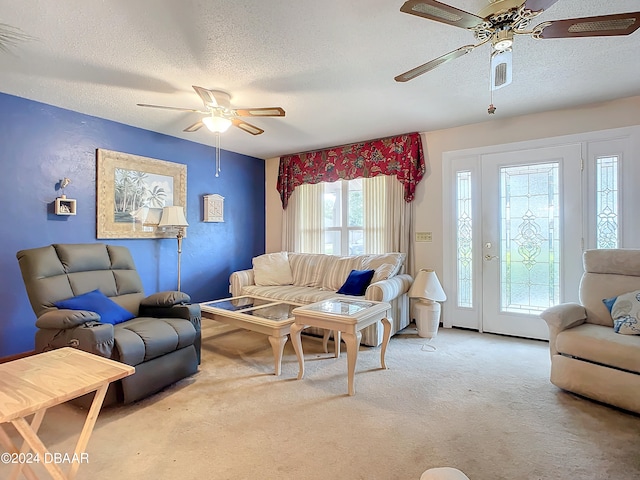 living room featuring ceiling fan, a textured ceiling, and light colored carpet