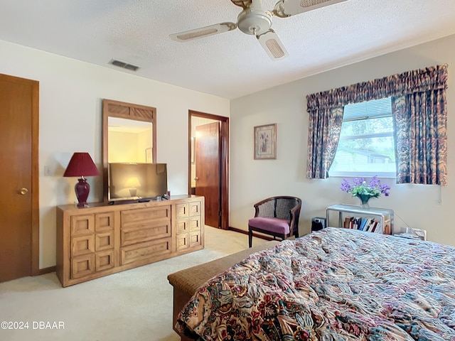 bedroom with a textured ceiling, light carpet, and ceiling fan