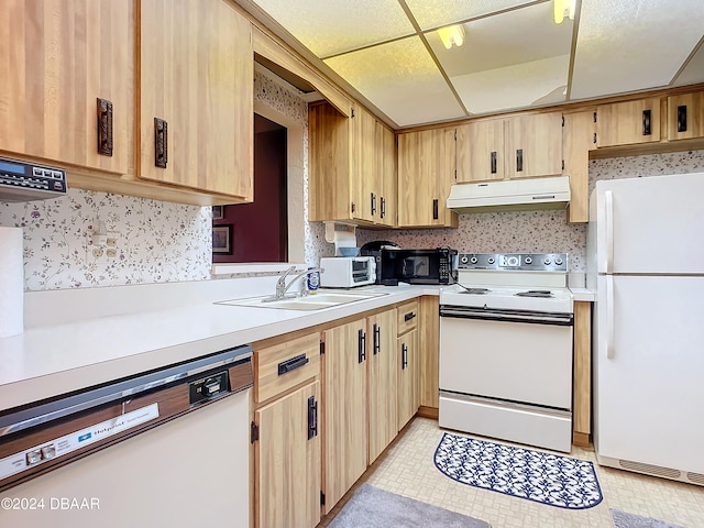 kitchen with light brown cabinetry, a paneled ceiling, white appliances, and sink