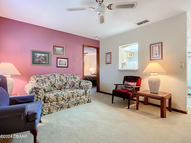 living room with ceiling fan, light colored carpet, and a textured ceiling