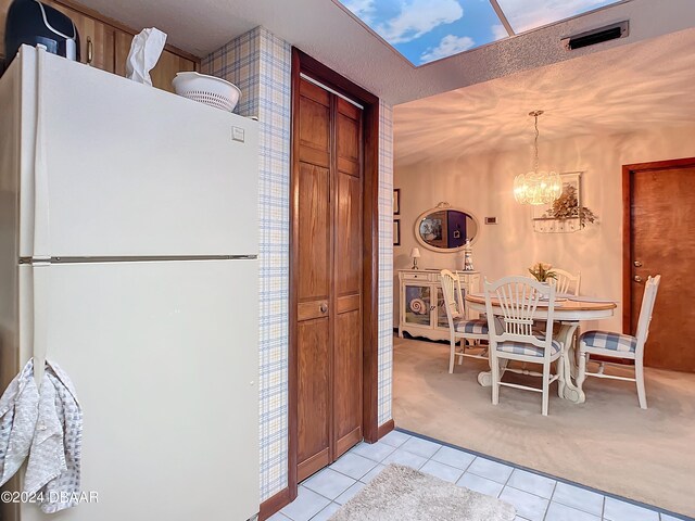 kitchen with white fridge, decorative light fixtures, a notable chandelier, a textured ceiling, and light colored carpet