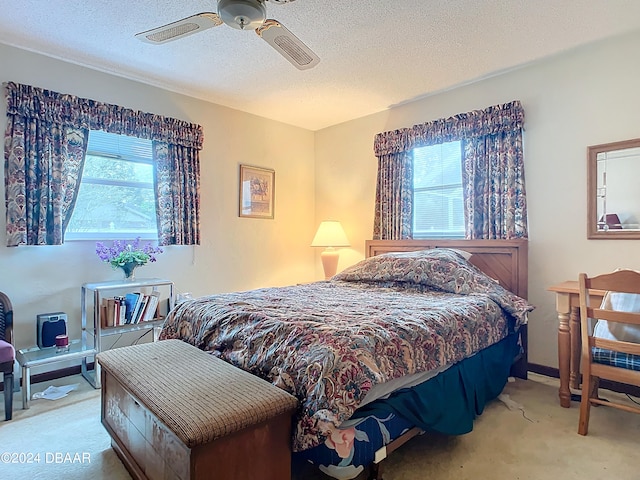 bedroom with multiple windows, a textured ceiling, light colored carpet, and ceiling fan