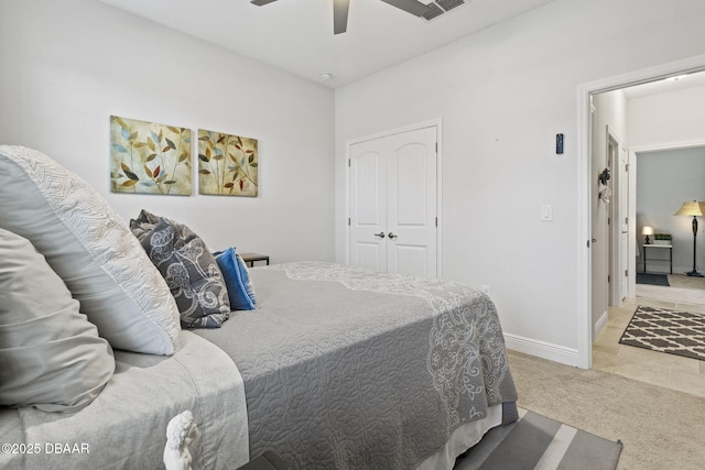 bedroom with ceiling fan, light colored carpet, and a closet