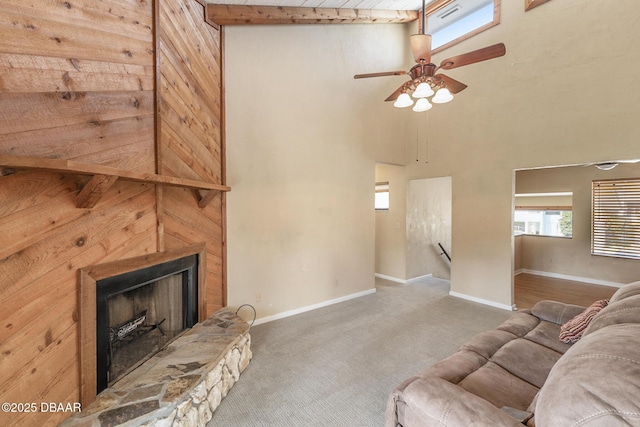 living room with a stone fireplace, carpet floors, and a high ceiling