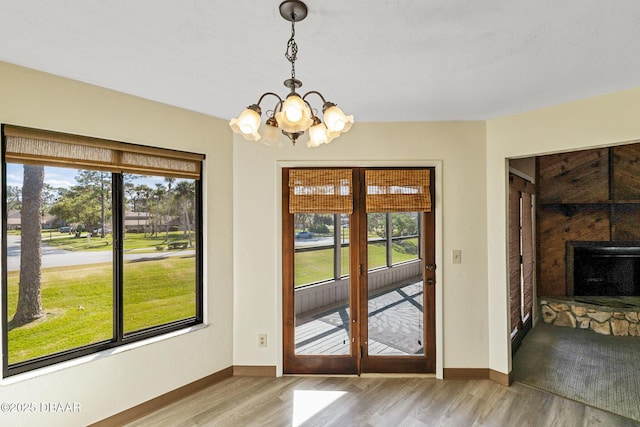 doorway to outside with a healthy amount of sunlight, a chandelier, and light wood-type flooring