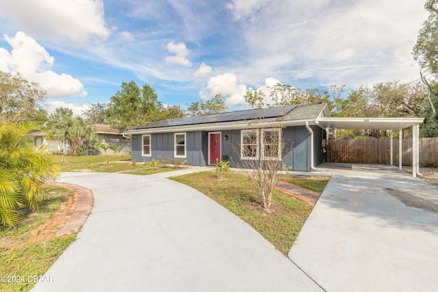 single story home featuring a front yard, solar panels, and a carport