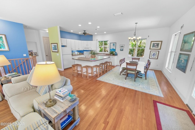 dining room featuring light wood-style floors, recessed lighting, a notable chandelier, and baseboards