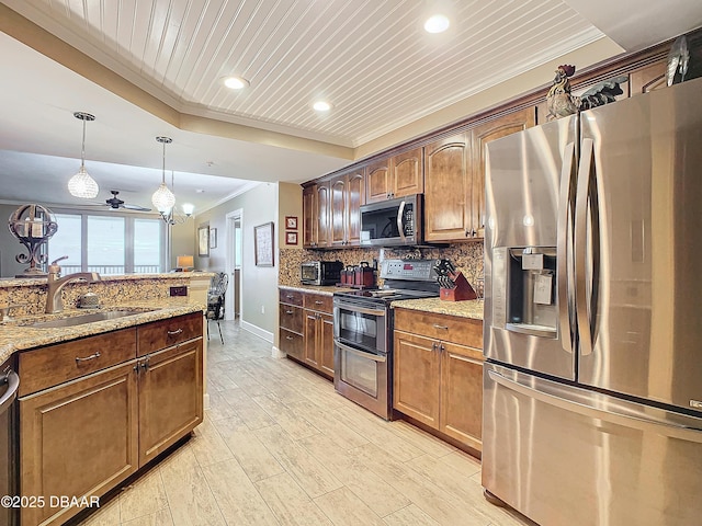 kitchen with light stone counters, decorative light fixtures, appliances with stainless steel finishes, ceiling fan, and sink