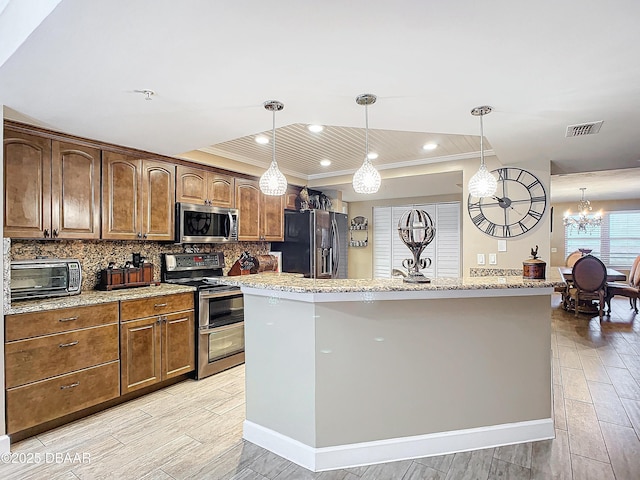 kitchen featuring light stone counters, decorative light fixtures, tasteful backsplash, a kitchen island with sink, and appliances with stainless steel finishes