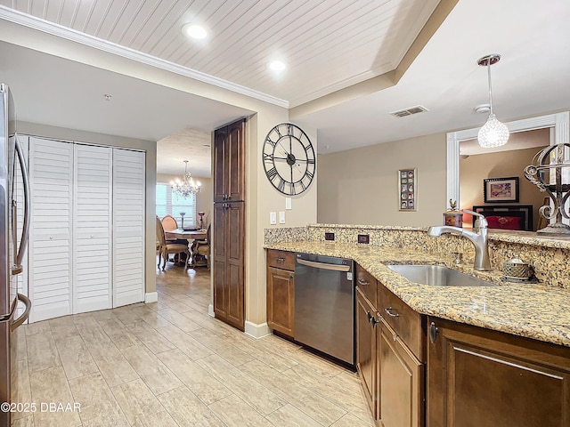 kitchen featuring sink, decorative light fixtures, light stone countertops, and appliances with stainless steel finishes