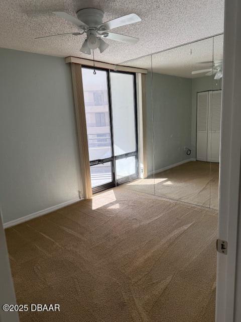 empty room featuring a textured ceiling, ceiling fan, carpet flooring, and a healthy amount of sunlight