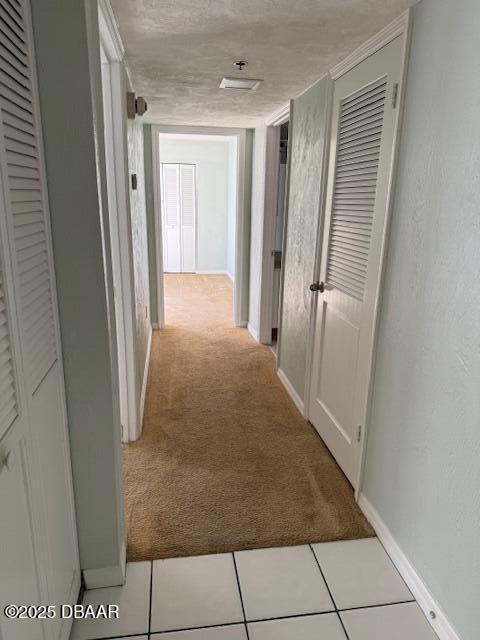 hallway with light carpet and a textured ceiling