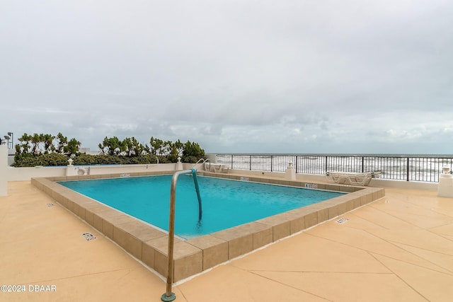 view of pool featuring a patio area and a water view