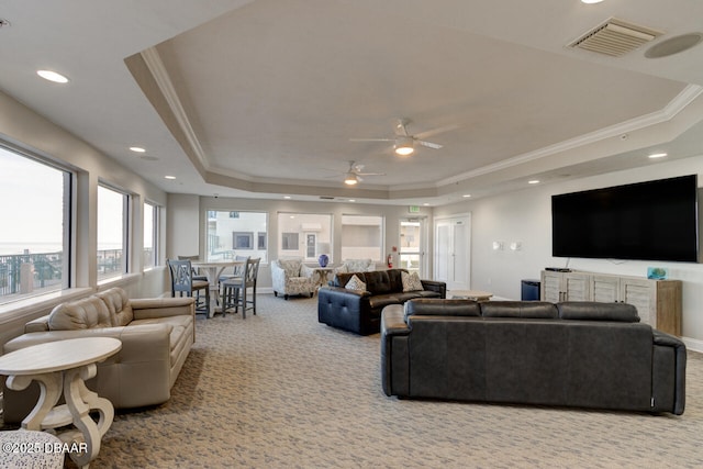 living room featuring crown molding, light colored carpet, a raised ceiling, and ceiling fan