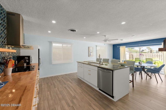 217 Royal Dunes Cir, Ormond Beach, FL 32176 - kitchen with dishwasher, wall chimney range hood, a textured ceiling, light wood finished floors, and white cabinets