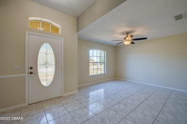 entrance foyer featuring light tile patterned floors, ceiling fan, baseboards, visible vents, and a textured ceiling
